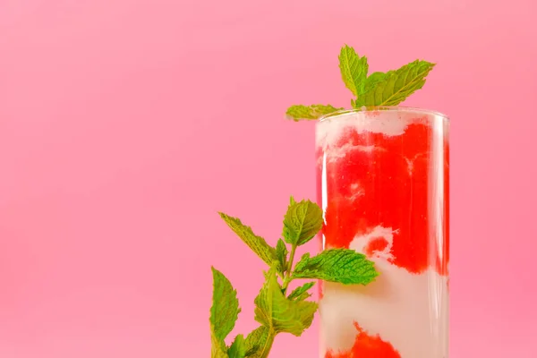 Aardbeiencocktail.Berry smoothies. Roze cocktail en crème in een transparante beker met aardbeien en munttakjes op een roze achtergrond. Zomer cocktails en drankjes. — Stockfoto