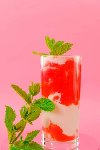 Jahodový koktejl. Bobulové koktejly. koktejl se smetanou v průhledném poháru s jahodami a mátovými výhonky na růžovém pozadí. Letní koktejly a nápoje. — Stock fotografie