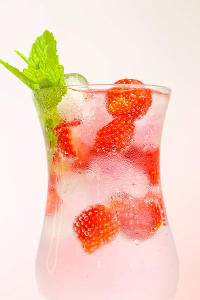 Jahodový nápoj. Letní pití. Osvěžující koktejl. voda ve sklenici s ledem a jahodami. Minerální voda s ledem a jahodami ve skleněném poháru a zralé jahody — Stock fotografie