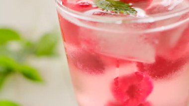 Raspberry cocktail. Ice cubes with raspberries in a glass with mineral water