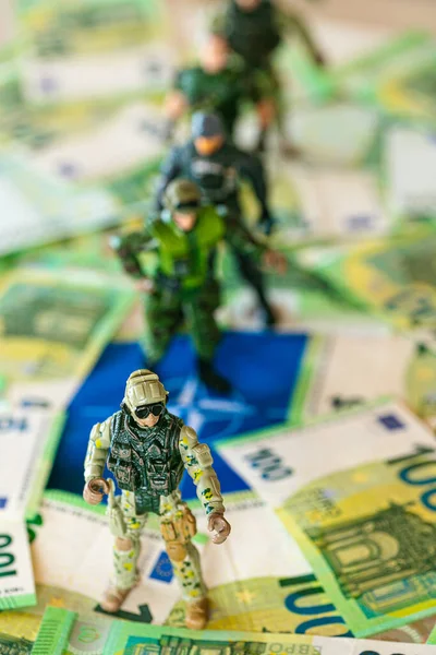 Military spending of NATO countries.Military figurines in NATO flag and euro banknotes. Military budget of NATO NATO.Money for armaments and troops