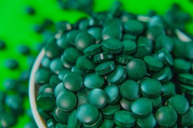 - Kasede bir çeşit ilaç var. Yeşil spirulina tabletleri yeşil arka planda. Brüksel yosun tabletleri. Vitaminler ve beslenme takviyeleri. Daha besleyici yiyecekler. Sağlıklı bir yaşam tarzı için gıda takviyeleri.