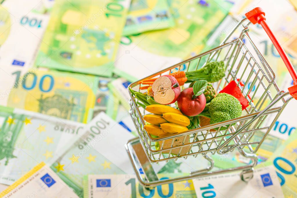 Food basket in Europe. Grocery basket in Europe.food crisis. Rising food prices in the European Union. supermarket trolley with groceries on euro banknotes background.