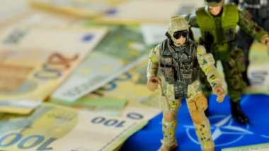 Army of European countries.Military exercises in Europe. Military figurines in NATO flag and euro banknotes.Money for armaments and troops.Military spending .Military budget of NATO countries.
