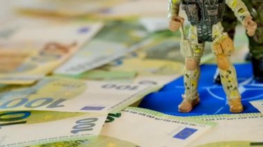 Army of European countries. Military figurines in NATO flag and euro banknotes.Money for armaments and troops.Military spending of NATO countries.Military budget.Military exercises in Europe.