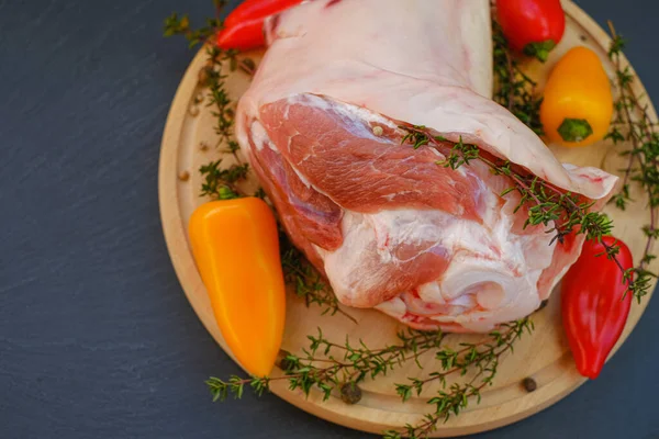 Kemikte domuz eti, taze biber ve tahta bir tahta üzerinde kekik. Arka planda et ürünleri..