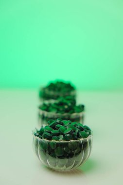 Açık yeşil bir arka planda şeffaf bardaklarda, alg tabletleri. Yeşil spirulina tabletleri. Vitaminler ve diyet takviyeleri. Daha fazla yiyecek. Yiyecek takviyeleri. 