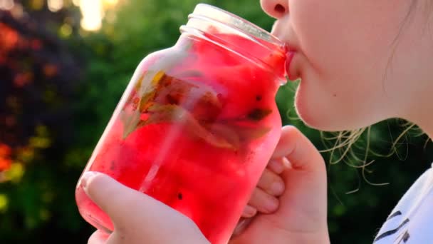 Watermelon drink.lgirl drinks a watermelon drink from a mug in a summer garden — Vídeo de stock