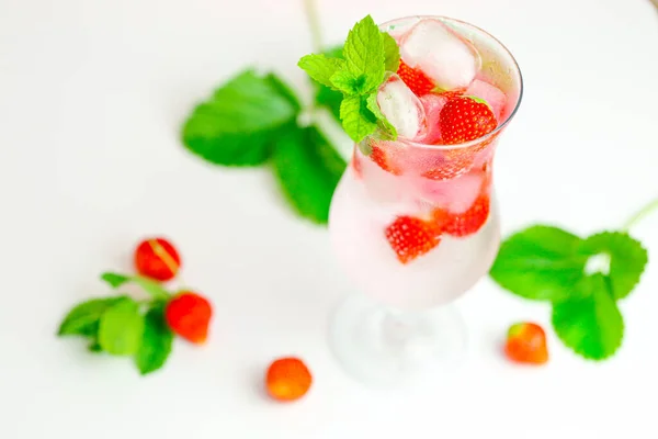 草莓饮料。夏天的鸡尾夏天的鸡尾矿泉水，有冰块的矿泉水，还有粉色背景上有叶子的成熟草莓 — 图库照片