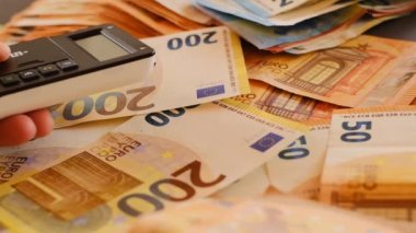 Banka kartıyla ödeme. Para transferleri. İnternetten faturaları ödüyorum. İnternetten alışveriş. Avro banknotlarının arka planında kart okuyucusuna plastik kart yerleştiren eller