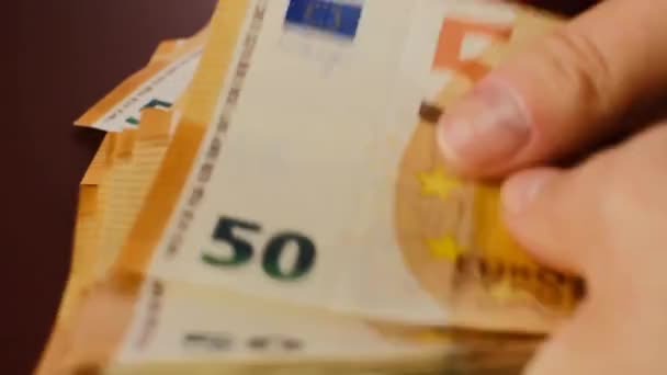 Recalculation of money. Expenses and incomes in European countries.Euro currency.fifty euros banknotes pack. hands count euro bills close-up on a brown background.Euro currency exchange rate. — Stock Video