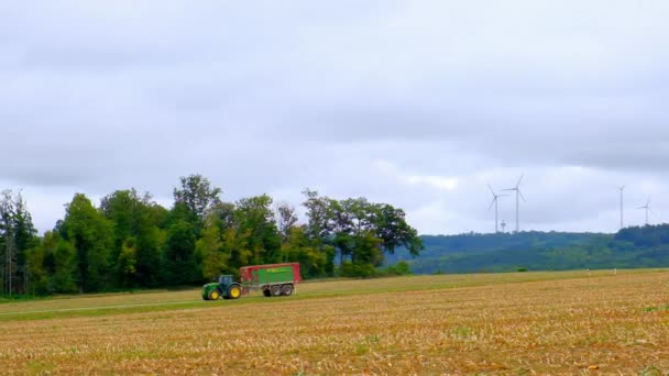 Tractor in het veld op windturbines achtergrond. Oogsten van tarwe.Landbouw en landbouw concept — Stockvideo