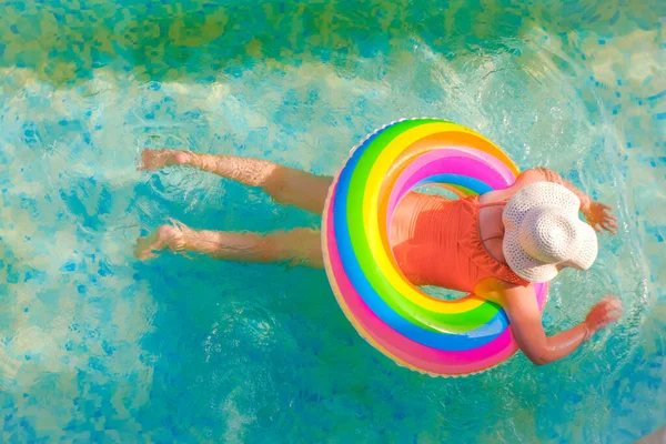 El niño nada en la piscina.Temporada de baño.Tiempo de verano y vacaciones. Chica con un anillo inflable arco iris en la piscina en un día soleado de verano. Tiempo de verano. —  Fotos de Stock