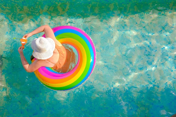 Niño en la piscina.Temporada de baño.Tiempo de verano y vacaciones. Chica con un anillo inflable arco iris en la piscina en un día soleado de verano. Tiempo de verano. Vista desde arriba. —  Fotos de Stock