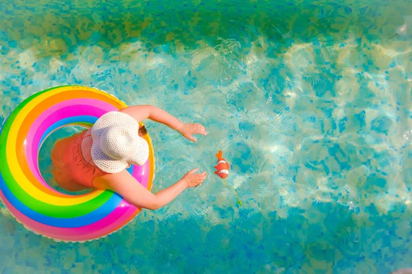 El niño nada en la piscina.Temporada de baño.Tiempo de verano y vacaciones. Chica con un anillo inflable arco iris en la piscina en un día soleado de verano. Tiempo de verano. Vista desde arriba. —  Fotos de Stock