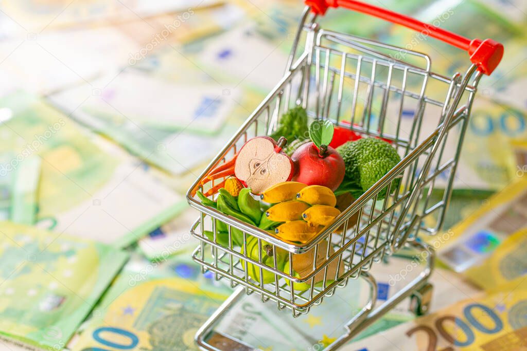  food prices in the European Union.supermarket trolley with groceries on euro banknotes background.Grocery basket in Europe. food crisis.