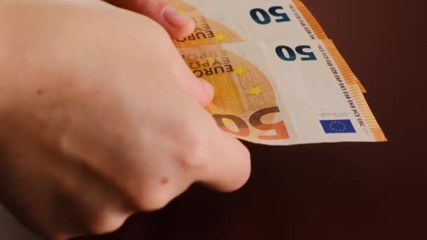 Recalculation of money.Euro currency exchange rate.fifty euros banknotes.Expenses and incomes in European countries. hands count euro bills on a brown background.Budget allocation.Money in hands. — Stock Video