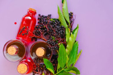 Mürver şurubu. Sambucus meyvesi. Şişede şerbet ve mor bir arka planda bir demet mürver..