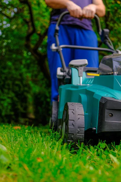 Lawn mowing. lawn mower close-up mows the lawn in the summer garden.Technique and equipment for the garden. Summer work in the garden. A man cuts green juicy grass with a lawn mower in a garden