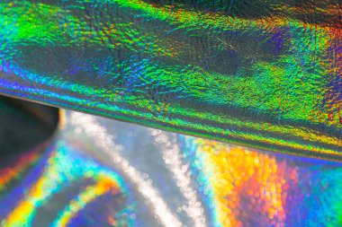 Holografik duvar kağıdı gümüş, mor ve yeşil renklerde. Yanardöner dalgalar ve kıvrımlı doku. Güzel metalik parlak kumaş. Metal holografik malzeme..