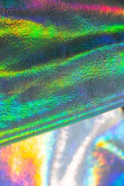 Holografik duvar kağıdı gümüş, mor ve yeşil renklerde. Yanardöner dalgalar ve kıvrımlı doku. Metalik parlak kumaş. Metal holografik malzeme..