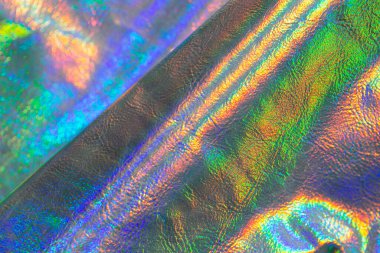 Yanardöner dalgalar ve kıvrımlı holografik doku. Güzel metalik parlak kumaş. Soyut trend holografik arka plan. Metal holografik materyal.