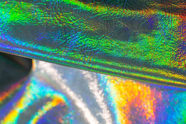 Holografik duvar kağıdı gümüş, mor ve yeşil renklerde. Yanardöner dalgalar ve kıvrımlı doku. Güzel metalik parlak kumaş. Metal holografik malzeme..