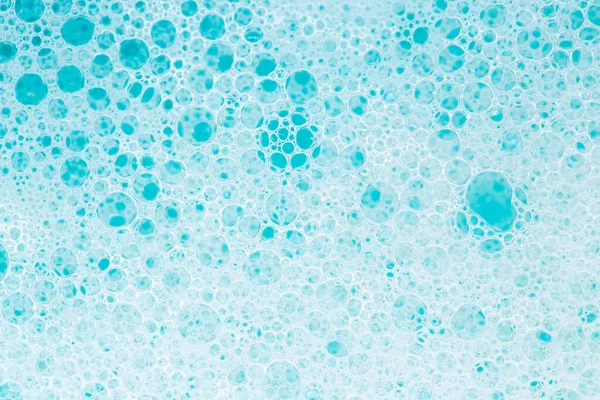 Blue water with foam bubbles.Cleanliness and hygiene background. Foam Water Soap Suds.Texture Foam Close-up. blue soap bubbles background.Laundry and cleaning background.foam bubbles.