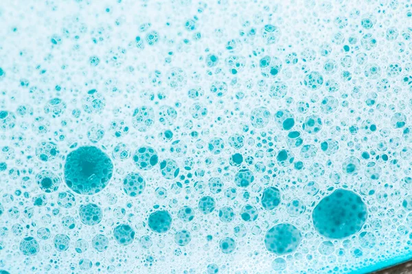 Blue water with white foam bubbles. Foam Water Soap Suds.Texture Foam Close-up. blue soap bubbles background.Laundry and cleaning background.foam bubbles.Cleanliness and hygiene background.