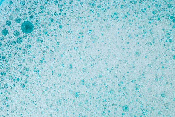 water with white foam bubbles.Cleanliness and hygiene. Foam Water Soap Suds.Texture Foam Close-up. blue soap bubbles background.Laundry and cleaning background.foam bubbles.