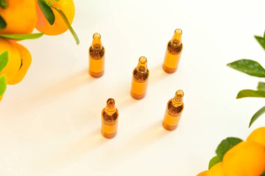 C vitamini. C vitamini solüsyonlu ampuller ve arka planda mandalina çalıları. Güzellik ve sağlık. C vitamini iğneleri, yeşil yapraklı narenciye meyveleri. Sağlık ve tıp konsepti..