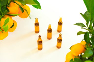 C vitamini. C vitamini çözeltisi olan cam ampuller ve arka planda mandalina çalıları. Güzellik ve sağlık. C vitamini iğneleri, yeşil yapraklı narenciye meyveleri. Sağlık ve ilaç.
