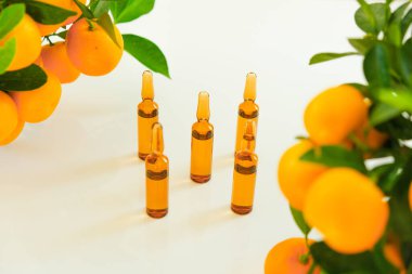C vitamini vitamini, C vitamini ve arka planda mandalina çalıları. Güzellik ve sağlık. C vitamini iğneleri, yeşil yapraklı narenciye meyveleri.