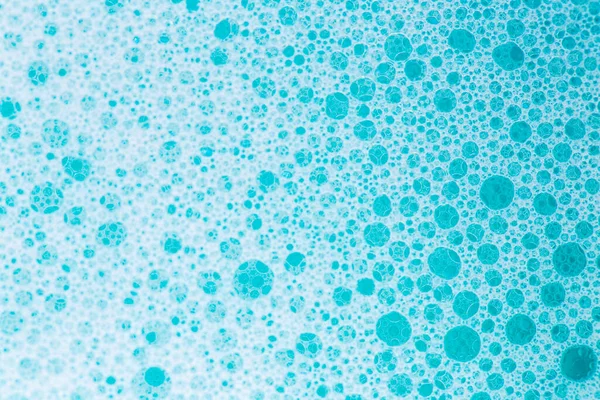 Blue water with white foam bubbles.Cleanliness and hygiene background.blue soap bubbles background. Foam Water Soap Suds.Texture Foam Close-up.