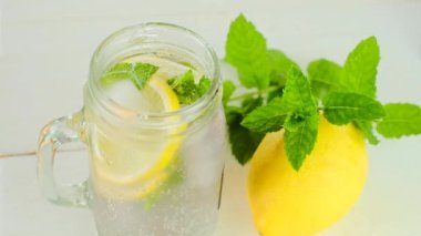 Limon içeceği. Nane şekeri bardağa dökülür. Kokteylle birlikte. Şeffaf sisli bardakta buzlu limonlu nane suyu. Nane yapraklı Citrus kokteyli. Şımarık limon suyu. limon suyu. Yavaş çekim. 