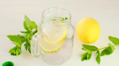 Puslu bardakta limonlu nane suyu. Maden suyu bardağa doluyor. Yüksek kalite 4k görüntü