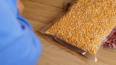 Yiyecek tedarikçisi. Pilav, bezelye, spagetti, vakumlu poşetlerde fasulye. Elleri masaya istiflenmiş. Erzak stokları. Depolama ürünleri.. 