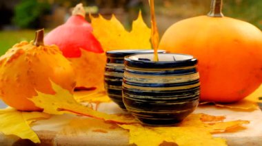 Hot tea is poured into striped mugs.mugs with hot drink and pumpkins with maple leaves in a cold autumn garden.Steam over a mug of hot tea. Cozy tea party in the autumn garden. Autumn cozy mood