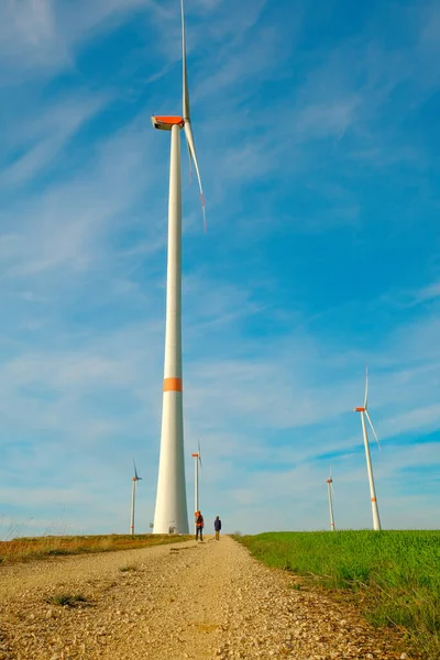 Wind generators.Wind energy.Inspection of wind turbines.Windmills and People near on the road on a blue sky background.Alternative energy sources.