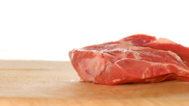 Domuz eti. El, tahta kesme tahtasına et parçaları koyar. 4k görüntü