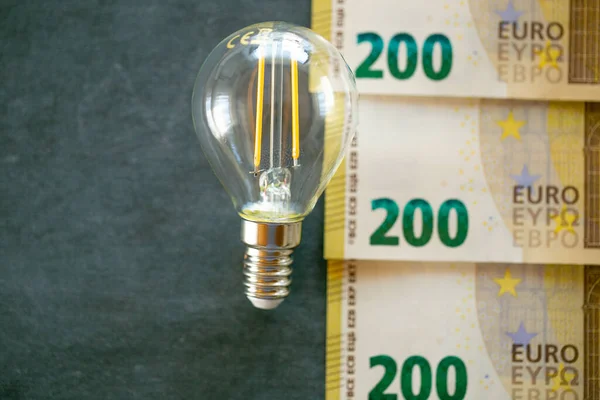 Electricity cost. Light bulb, euro banknotes and coins .Increasing the cost of light and heat.Rising electricity prices in Europe.Saving electricity concept.Crisis of energy production in the EU