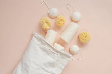 Sıfır atık hijyen ürünleri seti. Doğal konyak süngerleri ve lif bezleri ve bej ışıklı arka planda bej bir pamuk torbası. Çevre dostu biyolojik doğal kozmetik. Makul tüketim. 