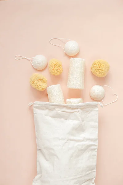 Natural cognac sponges and loofah washcloths and a beige cotton bag on a beige light background.Zero waste. reasonable consumption