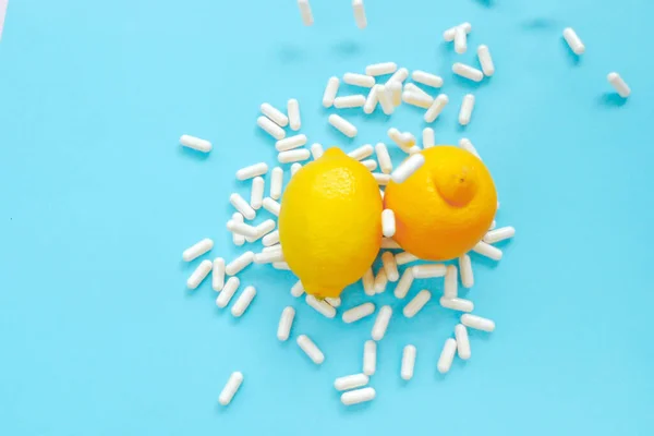 Vitamin C and citrus fruits. Flying vitamin C white pills and yellow lemons on a blue background.Natural Fruit Vitamin C.Immunity remedy. Health and medicine concept.
