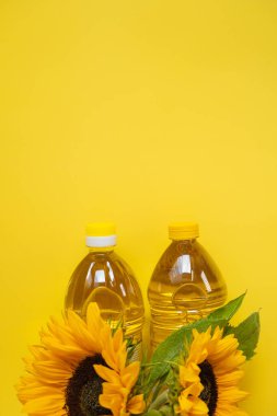 Sunflower oil. Oil bottles and sunflowers on a bright yellow background.Organic natural sunflower oil. Edible oils.top view, copy space. 
