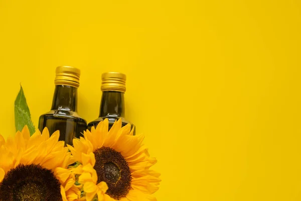 Sunflower oil. Oil bottles set and sunflowers blooming on a bright yellow background.Organic natural farm sunflower oil. Edible oils.top view, copy space.