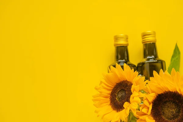 Sunflower oil. Oil bottles and sunflowers on a bright yellow background.Organic natural farm sunflower oil. Edible oils.top view, copy space.
