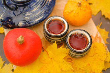 Autumn tea.Tea drinking.teapot and two striped cups in the garden on a sunny autumn day.mugs with hot drink and pumpkins with maple leaves.Cozy tea party in the autumn garden.