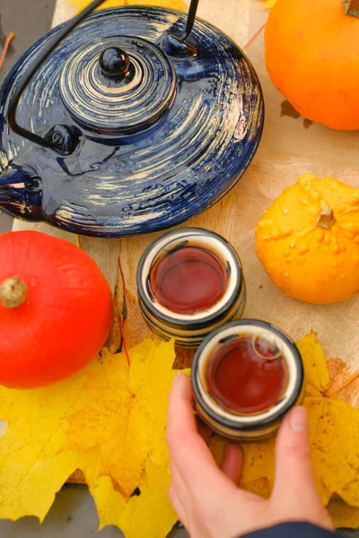 Autumn tea in the garden on a sunny autumn day.mugs with hot drink and pumpkins with maple leaves.Cozy tea party in the autumn garden. Autumn cozy mood