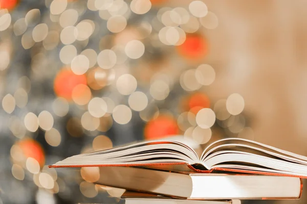 Christmas books. Winter books.Stack of books on the table on shining twinkling garlands background.Cozy reading in the winter.Christmas tales, stories, myths and legends.Reading during winter holidays